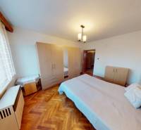 Bedroom in a family house with a bed and a wardrobe, floor with wooden decor.