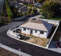 A family house under construction in Horné Štitáre with surrounding buildings and an asphalt road.