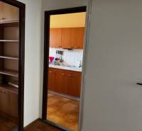A hallway with an entrance to the kitchen, a floor with a wooden decor in a 3-room apartment.