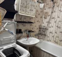 Bathroom in a 3-room apartment with a bathtub, sink, and washing machine, wallpaper decoration.