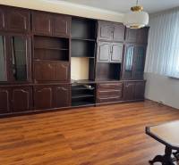 Living room in a three-room apartment with a wooden decor floor, dark furniture.