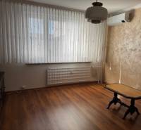 A room with a wooden floor decor and a table in a three-room apartment.