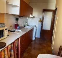A kitchen in a 3-room apartment with a wooden decor floor, white cabinets, dining table.
