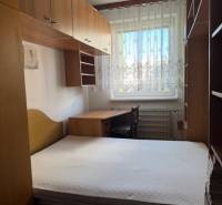 Bedroom in a 3-room apartment with a bed, wardrobes, and a window with lace curtains.