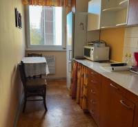 A kitchen in a 3-room apartment with a wooden decor floor and furniture in warm colors.