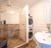 Bathroom with a shower, washing machine, and dryer, 3-room apartment, floor with wood decor.
