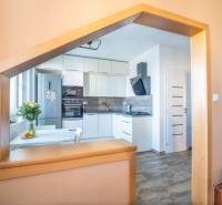 A kitchen in a 3-room apartment with modern appliances and a wooden decor floor.