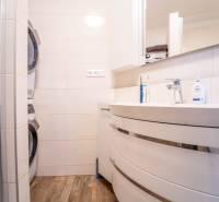 Bathroom with a washing machine and dryer in a 3-room apartment with a wooden decor floor.