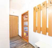 A hallway with coat racks, doors, and a floor with a wooden decor in a 3-room apartment.