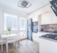 A kitchen in a 3-room apartment with a wooden decor floor and light furniture.