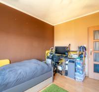 A room in a 3-room apartment with a bed, a desk, and a floor with a wooden decor.