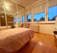 A bedroom in a 3-room apartment with a bed, wardrobe, and wooden decor flooring.