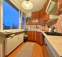 A kitchen in a 3-room apartment with light furniture and a wooden decor floor.