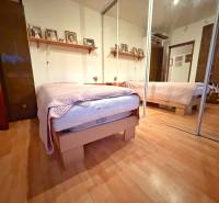 Bedroom in a 3-room apartment with a bed, mirrored wardrobe, and wooden decor flooring.