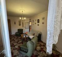 Living room in a three-room apartment with green furniture and a decorative carpet.