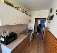 A kitchen in a 3-room apartment with a wood-patterned floor, appliances, and storage cabinets.