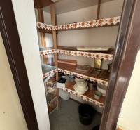 A pantry in a 3-room apartment with built-in shelves and stored kitchen supplies.