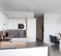 Kitchen of a 2-room apartment with white cabinets and a dining table, floor with wooden decor.