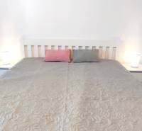 A bedroom with a bed, two pillows, and nightstands in a two-room apartment.