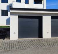 Garages on Predmerského Street in Trenčín with an apartment building in the background.