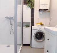 A bathroom with a shower, washing machine, and storage space in a 2-room apartment.