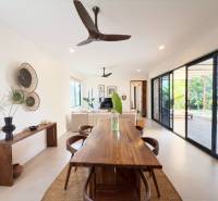 Dining room in a family house with a wooden table and a view of the yard through glass doors.