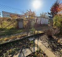 Gardens on Stredná Street in Bratislava-Ružinov with a fence and greenery.