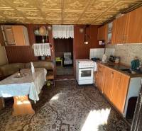 A kitchen with older furniture, a wooden decor floor, visible dining area.