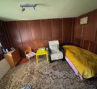 A room with chairs, a bed, a cabinet, and a decorative carpet in the Gardens.