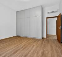 A room with a wooden decor floor, a built-in wardrobe, and white walls in a 4-room apartment.