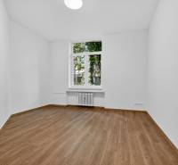 An empty room with light walls and a wooden decor floor in a 4-room apartment.