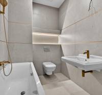 A bathroom with a bathtub, sink, gold faucets, and a toilet in a 4-room apartment.