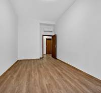 An empty room in a 4-room apartment with a wood-patterned floor and white walls.