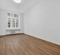 A room in a 4-room apartment with a wood-patterned floor and white walls.
