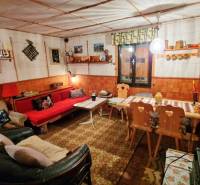 A cozy cabin interior with a decorated table, sofa, and wooden chairs.
