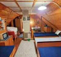 A wooden interior of a cabin with three beds and a television in a traditional style.