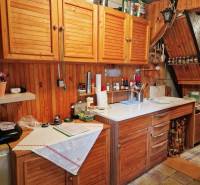 A kitchen in a cottage with wooden cabinets and a white countertop, cozy atmosphere.