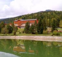 Mountain hotel surrounded by forests in Tále in Bystrá with a pond in the foreground.