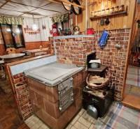 A kitchen corner in a cabin with wooden decor and a tiled stove in Tále in Bystrá.