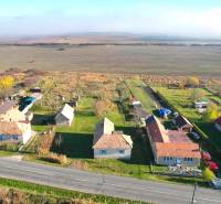 Houses by the main road in Radnovce, with plots - living surrounded by fields.