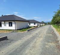 Family houses on Vyšná Šebastová Street in Prešov surrounded by greenery, next to an unfinished road.