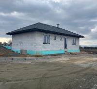 A family house under construction on Vyšná Šebastová street, surrounded by a gray sky and a gravel area.