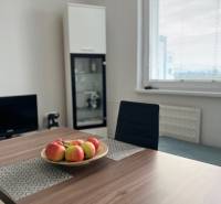 Dining table with a bowl of apples, chair, glass display cabinet, window.