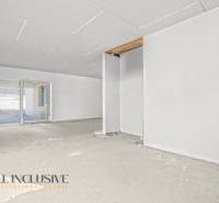 A spacious room in a family house with an unfinished floor and a large window.