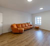 Living room with an orange sofa and a wooden decor floor in a two-room apartment.