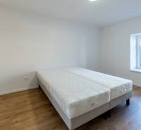 Bedroom in a 2-room apartment with a bed and a wooden decor floor.
