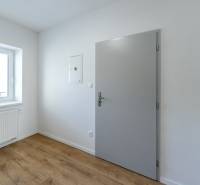 The interior of a room with white walls, a wood-patterned floor, and a window.