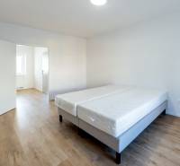 Bright room with a double bed and wood-decor flooring in a two-room apartment.