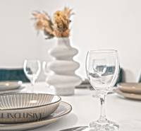 A table set with plates and glasses in a family home, a tasteful vase with flowers.
