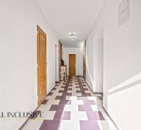 A hallway in a family house with a colorful geometric floor and wooden doors.